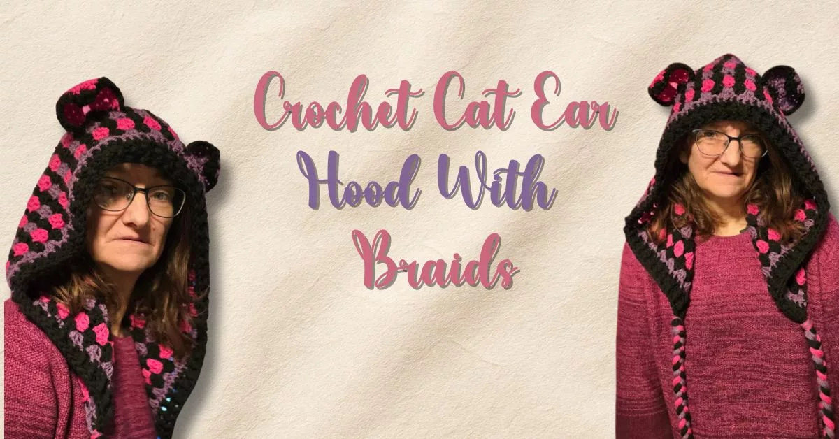 A person wearing a handmade crochet hood with cat ears and long braids in black, orchid, and bright pink yarn. They’re wearing glasses and a maroon sweater against a neutral beige background. Text on the image reads “Crochet Cat Ear Hood With Braids.”