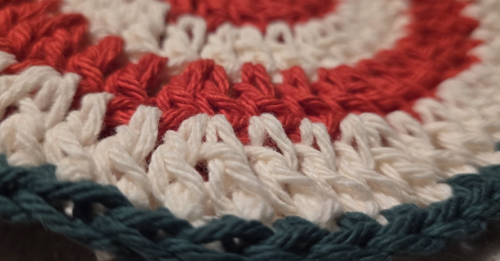Christmas crochet kitchen set showing red and ivory peppermint spiral circle coaster project